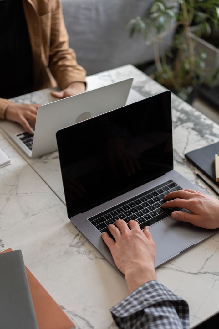 Two people working on laptops in a modern office setting, showcasing teamwork and productivity.